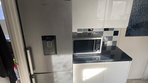 A kitchen with a stainless steel refrigerator, a microwave, and a water dispenser. - A real homely home close to Gatwick and the South East of England. (Crawley)
