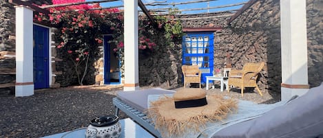 A cozy outdoor seating area with a table, chairs, and a cushioned bench.