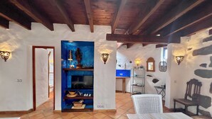 Un intérieur rustique avec des poutres apparentes, un mur d’accent bleu et un sol carrelé.