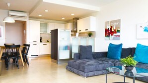 A modern living room with a grey sofa, a glass coffee table, and a dining area with a wooden table and chairs. - Amazing Sunset Golf-course Villa for up to 7 (San Bartolomé de Tirajana)
