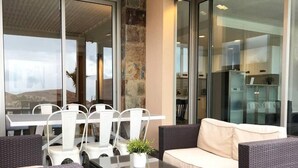 A modern outdoor seating area with a glass table, white chairs, and a beige sofa. - Amazing Sunset Golf-course Villa for up to 7 (San Bartolomé de Tirajana)