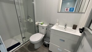Une salle de bain moderne avec une douche à parois de verre, des toilettes et un lavabo équipé d’un distributeur de savon.