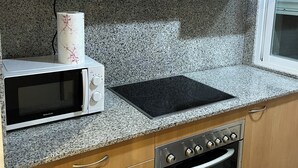 Eine Küche mit Holzausstattung, einer Mikrowelle, einem Herd und einem Backofen.