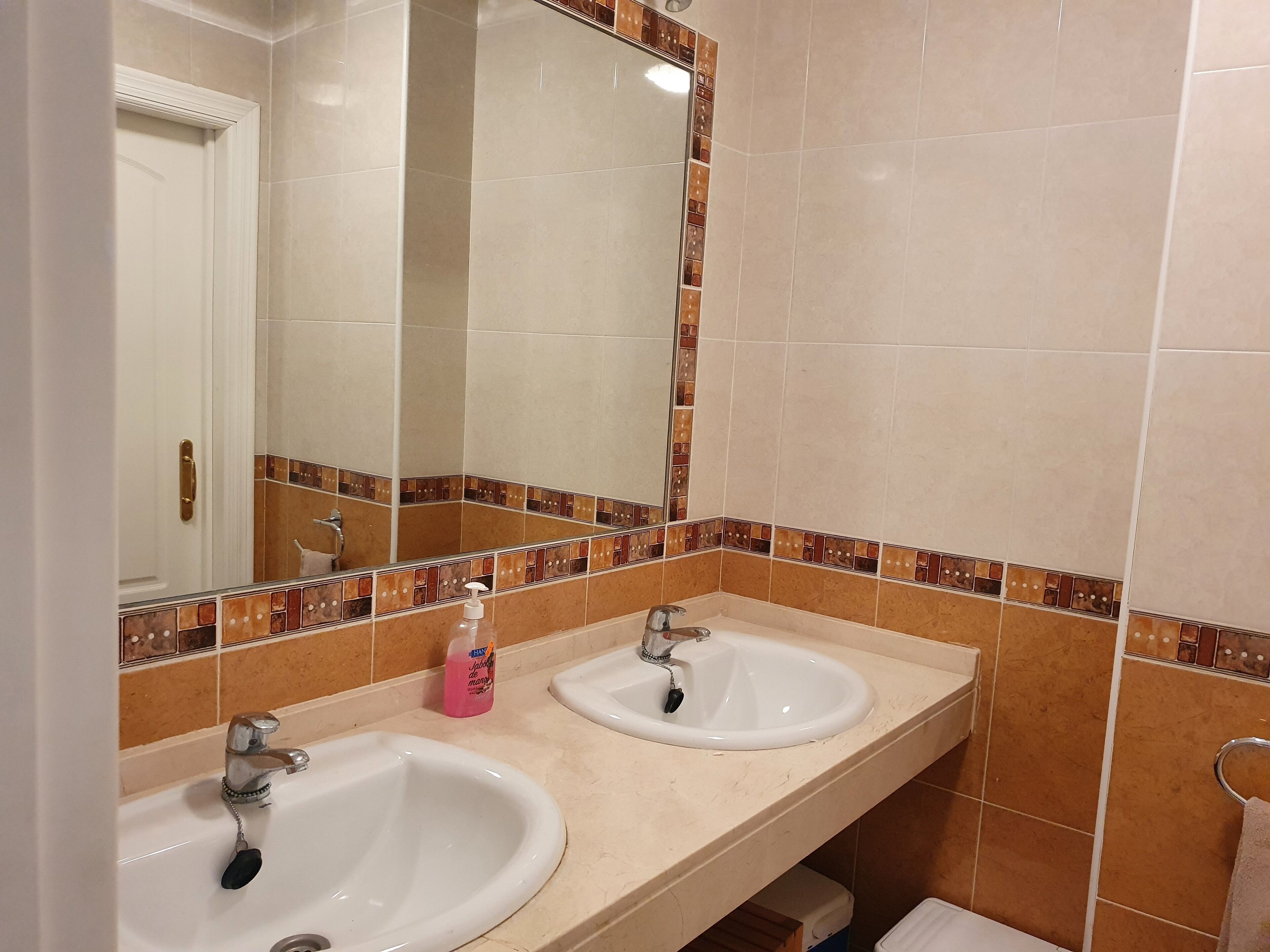 A bathroom with two sinks, a mirror, and a towel rack.