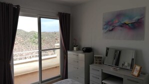 Una camera da letto con un letto, una scrivania, un comò, una finestra con tende e un quadro appeso al muro.
