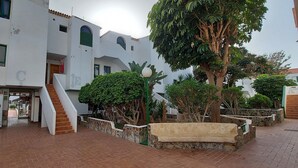 A courtyard with a staircase leading to a building entrance, surrounded by greenery and a stone bench. - 1 Bed Apartment - Sleeps 2 - Pool - Parking (Arona)