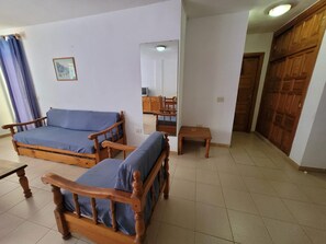A room with two wooden beds, a small table, a mirror, and a wardrobe. - 1 Bed Apartment - Sleeps 2 - Pool - Parking (Arona)