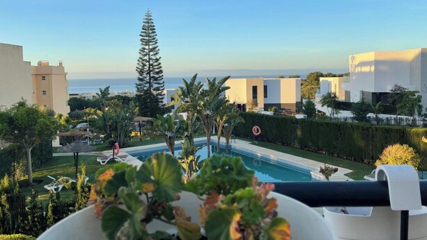 Ein Poolbereich mit Blick auf das Meer, umgeben von modernen Gebäuden und Grünflächen.