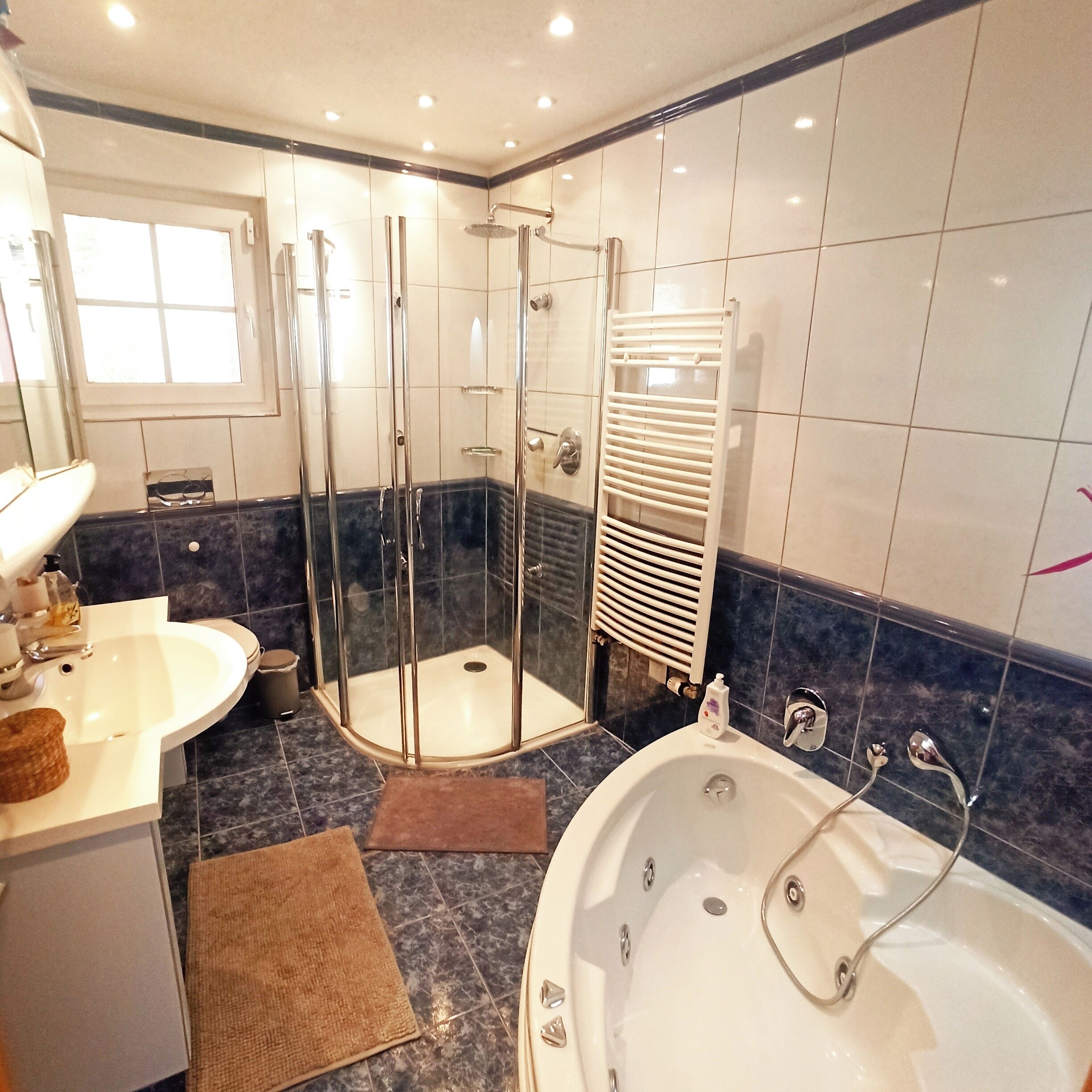 A modern bathroom with a glass-enclosed shower, a freestanding bathtub, and a vanity with a sink and mirror.