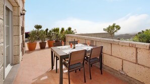 An outdoor patio with a table set for two, surrounded by potted plants and overlooking a scenic view. - Finca Aurora - Cozy 1-bed Apartment (Arico)