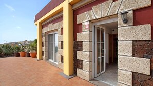A building with a stone facade, a yellow column, and a door leading to an interior space. - Finca Aurora - Cozy 1-bed Apartment (Arico)