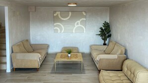 A living room with two beige sofas, a coffee table, and a potted plant. - Green Oasis Costa Casa Adosada con Vistas al Mar (Casares)