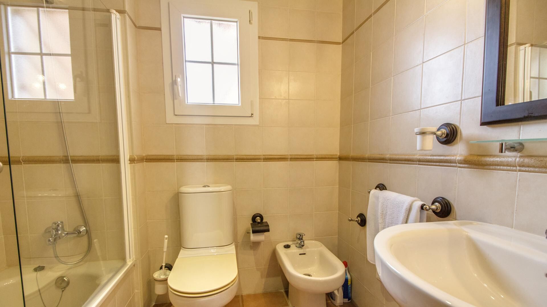 A bathroom with a toilet, bidet, bathtub, and a window.