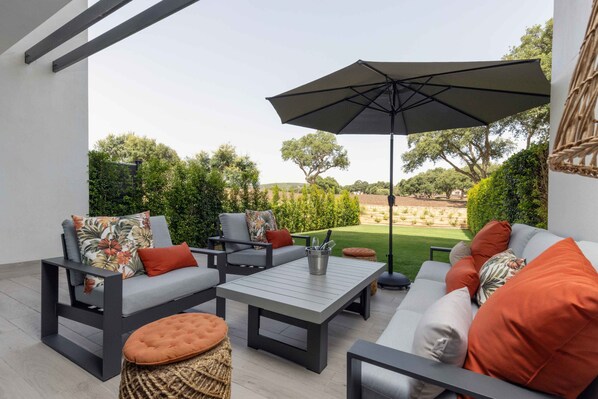 Un espace extérieur aménagé avec un canapé, des chaises, une table et un parasol.