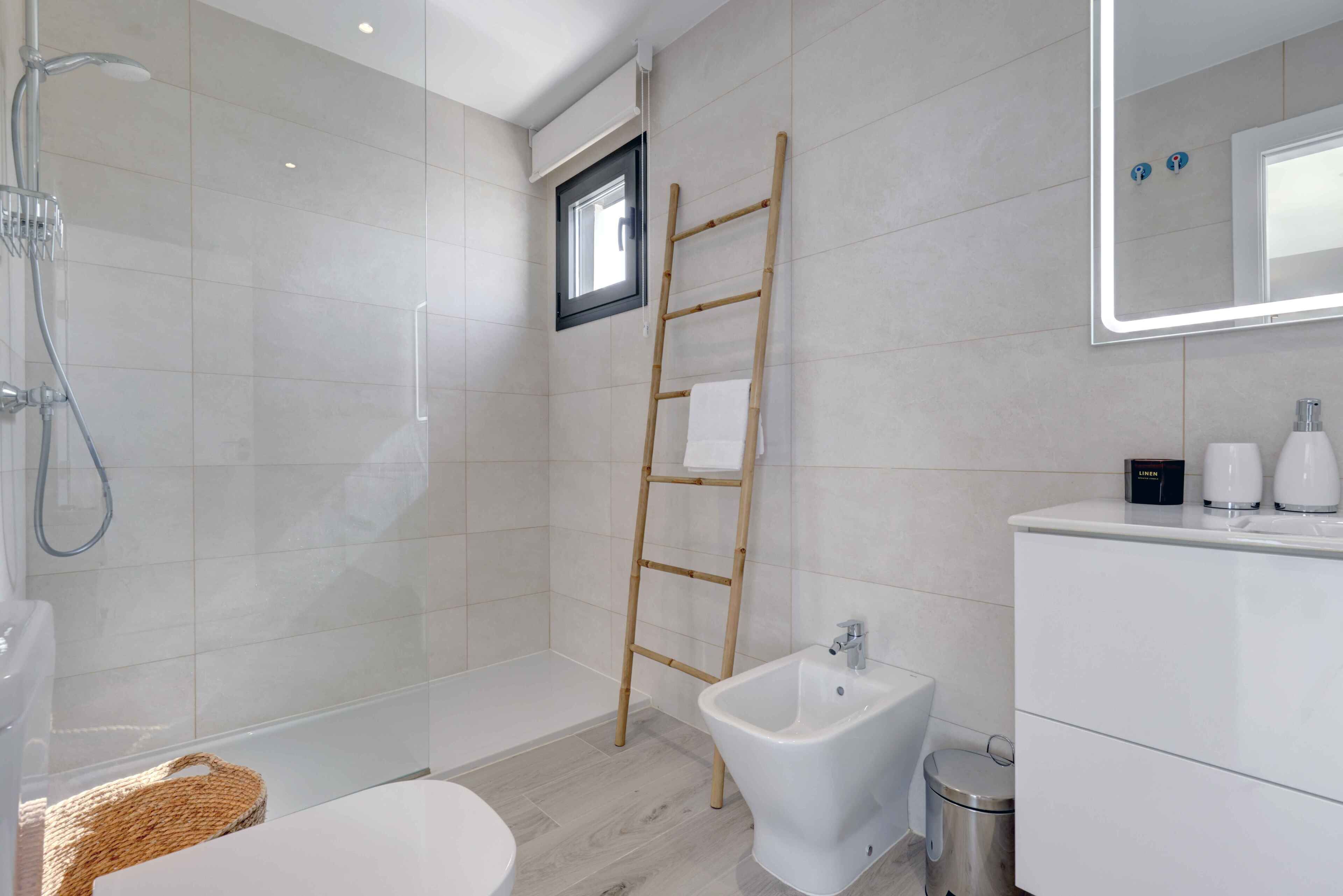 A modern bathroom with a shower, bidet, toilet, and a vanity with a mirror.