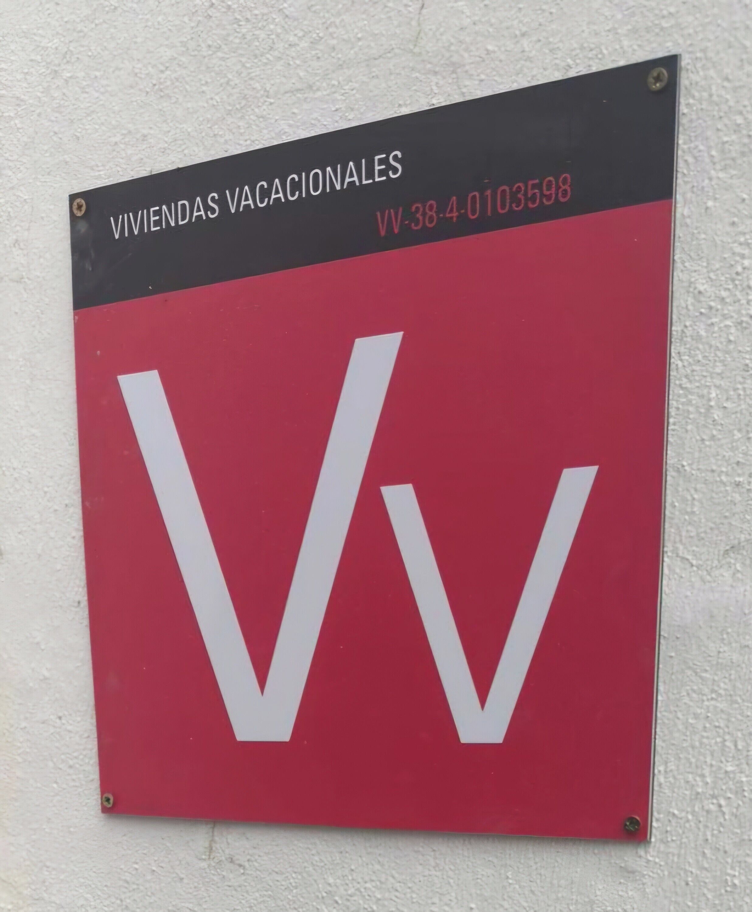 A sign with the text "VIVIENDA VACACIONALES" and a large white letter "V" on a red background.