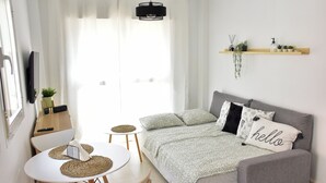 Une chambre moderne et bien éclairée, équipée d’un lit, d’un canapé, d’une table à manger et d’un téléviseur.