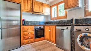 Une cuisine avec des meubles en bois, un réfrigérateur en acier inoxydable, un lave-vaisselle et un lave-linge.