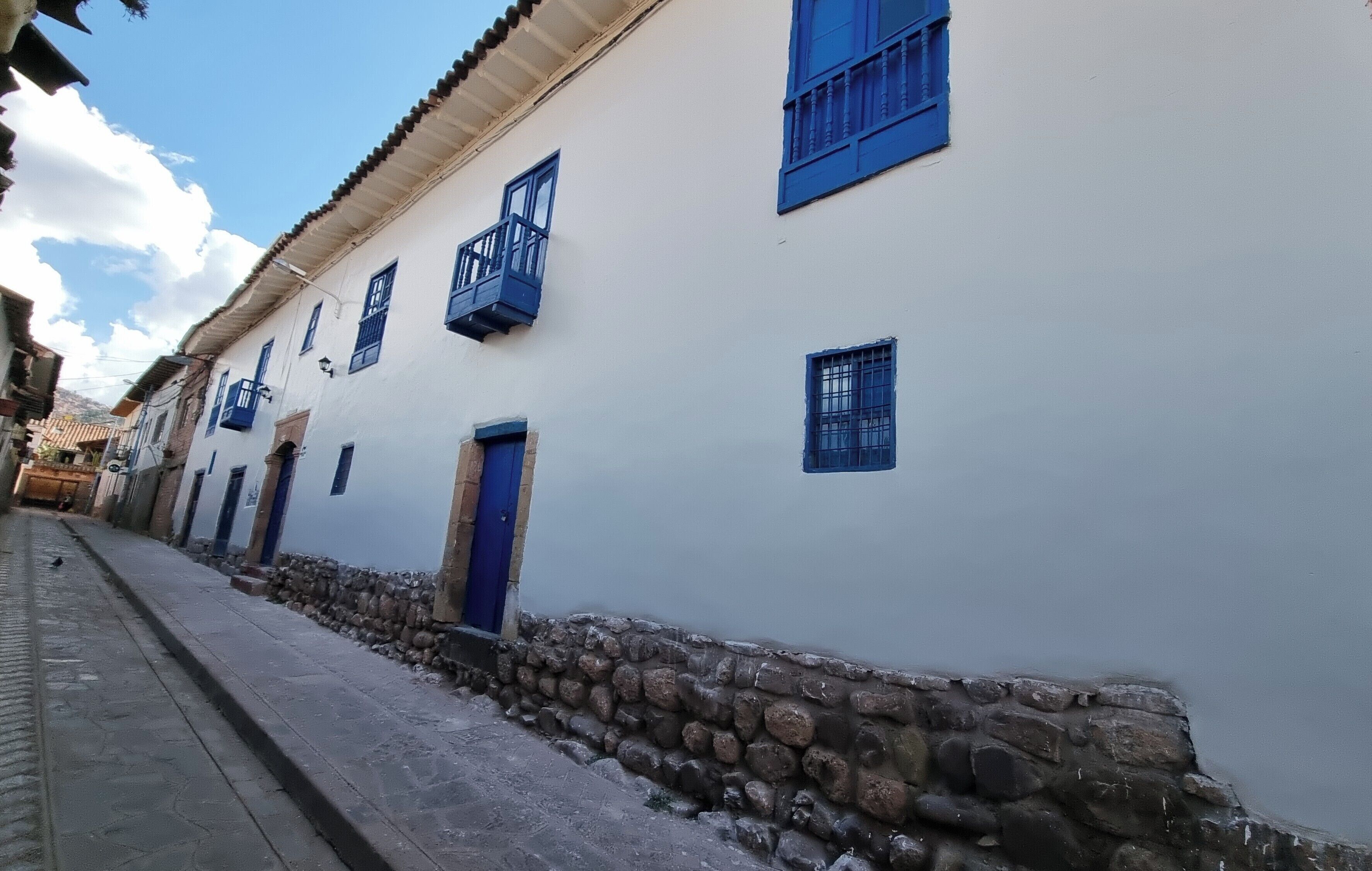 A white building with blue shutters and stone walls.