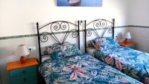 A bedroom with two single beds, a nightstand with a lamp, and a wall-mounted painting. - Beachfront House,sea Views Near Historic Cartagena (Cartagena)