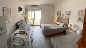 Una camera d'albergo con un letto, una poltrona, un tavolo con sedie e un balcone arredato con sedute.