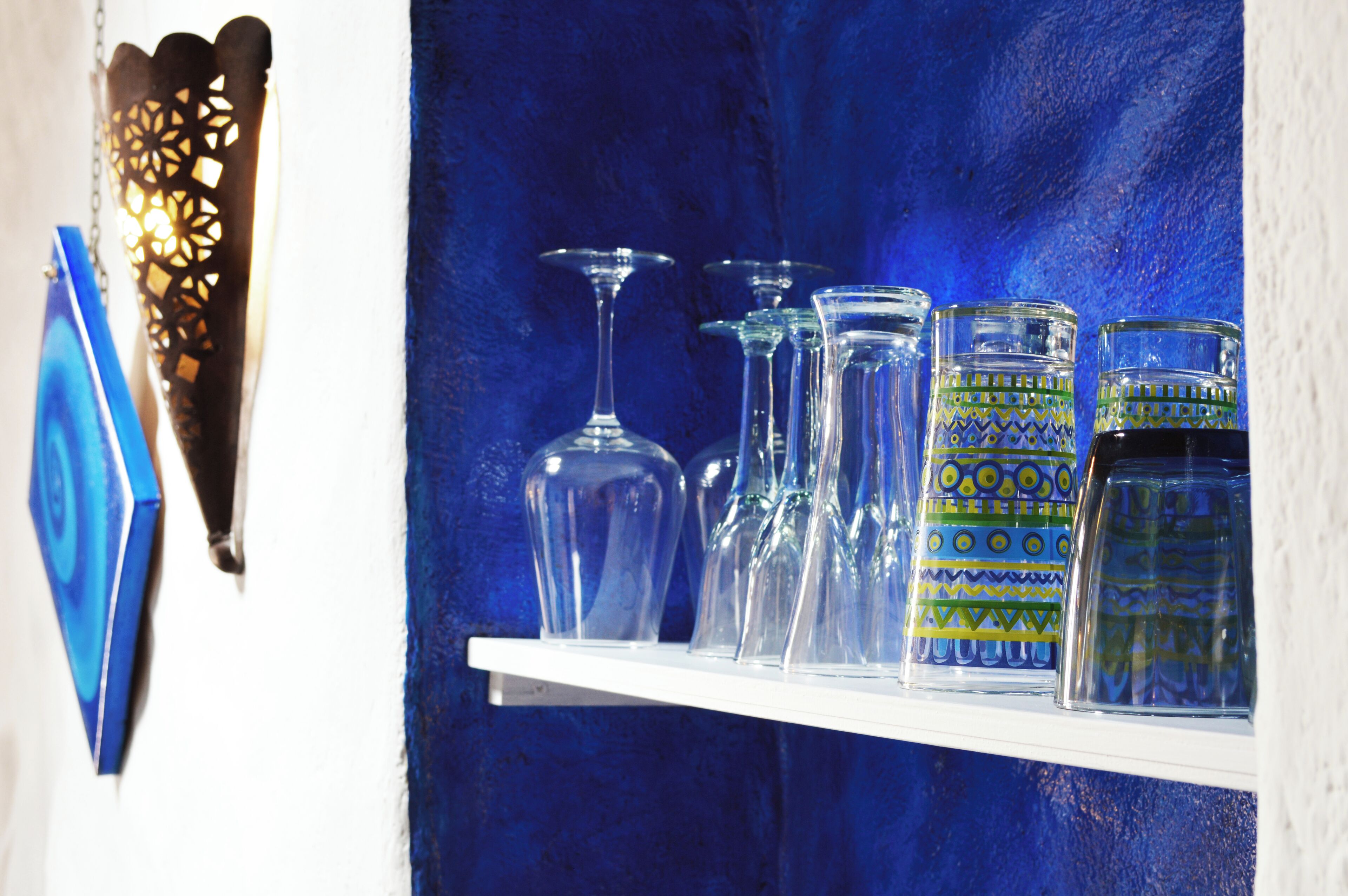 A shelf with various glassware against a blue background.