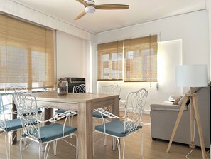 Una sala de estar moderna con una mesa de comedor, sillas, un sofá, una lámpara y un ventilador de techo.