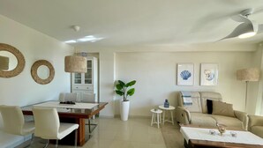 Un salon moderne comprenant un coin repas, un canapé, une table basse et un ventilateur de plafond.