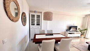 Un espace repas moderne avec une table en bois, des chaises blanches et un meuble avec des portes en verre.