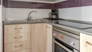 Una cucina compatta con mobili in legno, un lavello in acciaio inossidabile, una macchina da caffè e un forno.