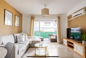 Una sala de estar con sofá, mesa de centro, televisor y balcón con vistas.