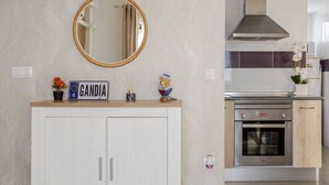 Una cucina con forno integrato, cappa aspirante in acciaio inox e pensile bianco sotto uno specchio.