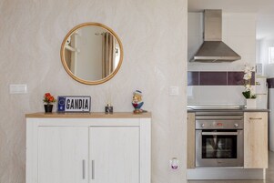 Una cocina con horno integrado, extractor de acero inoxidable y un mueble blanco debajo de un espejo.