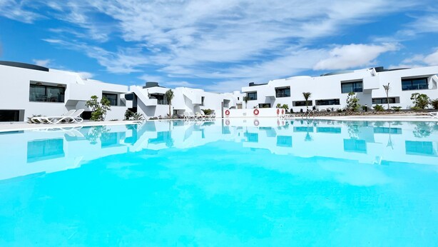 A modern hotel with a large pool, white buildings, and clear blue skies. - Superior Apartment Sleeps 2 With Pool (La Oliva)