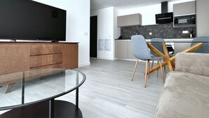 A modern living room with a flat-screen TV, a glass coffee table, and a sofa. - Superior Apartment Sleeps 2 With Pool (La Oliva)