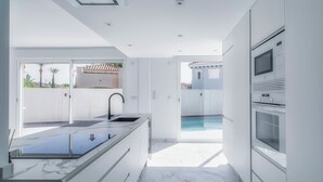 A modern kitchen with a marble countertop, built-in oven, and a view of a swimming pool. - Villa Fresno With Pool on Mar Menor Golf Resort (Torre-Pacheco)