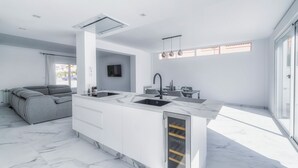 A modern kitchen with a marble countertop, a built-in sink, and a dining area with a table and chairs. - Villa Fresno With Pool on Mar Menor Golf Resort (Torre-Pacheco)
