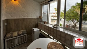 Een kamer met een groot raam, een radiator, een tafel en een lamp.