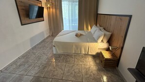 Een hotelkamer met een bed, een aan de muur bevestigde televisie, een raam met gordijnen en een klein rieten mandje.