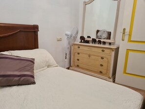 Cozy retreat with a single bed, dresser, and mirror.