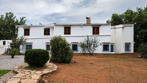 A two-story white building with a tiled roof, multiple windows with brown frames, and a stone pathway leading to the entrance. - House Sleeps 8 - Natural Pool, Pet Friendly, Views (Nules)