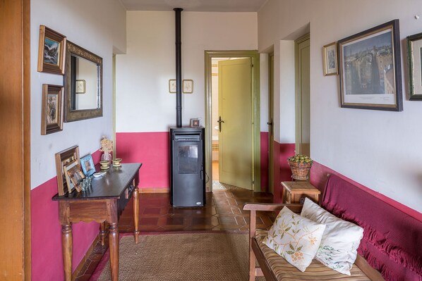 A cozy living room with a wooden table, a sofa with patterned cushions, and a wall adorned with framed pictures.