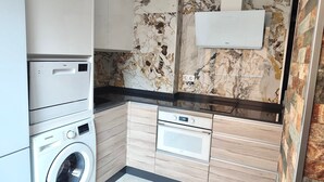 A compact kitchen with a washing machine, a microwave, and a built-in oven. - Amplio Apartamento Turistico en Torrevieja (Torrevieja)
