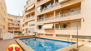 A multi-story building with a swimming pool, balconies, and a tiled exterior. - Amplio Apartamento Turistico en Torrevieja (Torrevieja)