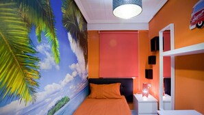 Ein Zimmer mit Bett, Nachttisch, Spiegel und einer Wandmalerei mit tropischer Szenerie.