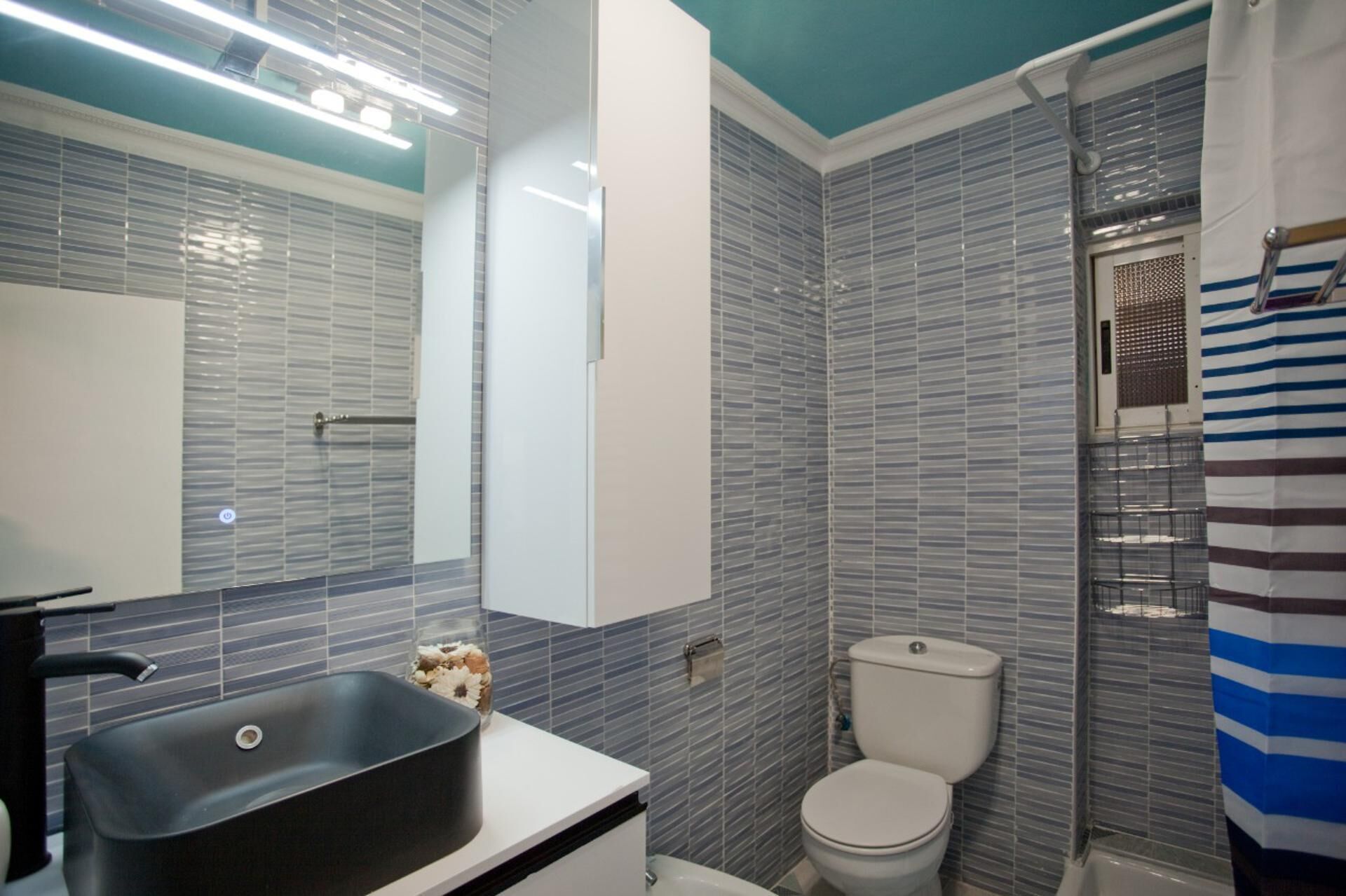 A bathroom with a modern design, featuring a sink, toilet, and shower area.