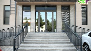 A building entrance with a set of stone steps, metal railings, and a glass door. - Parklane Hotel (Tashkent)