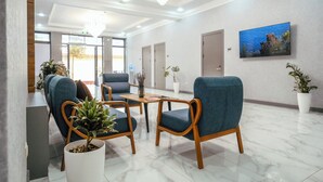 A modern lobby with seating, a chandelier, a painting, and potted plants. - Parklane Hotel (Tashkent)