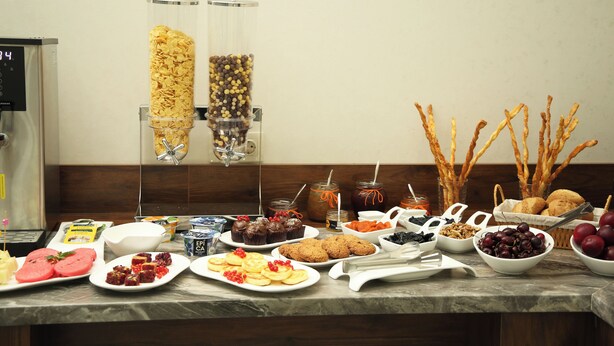 A buffet table with various food items and a coffee machine. - Parklane Hotel (Tashkent)