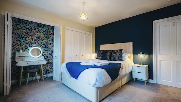 A bedroom with a bed, bedside tables, a vanity with a mirror, and a star-shaped ceiling light. - The Leam Terrace Escape 3 Bed Townhouse (Royal Leamington Spa)